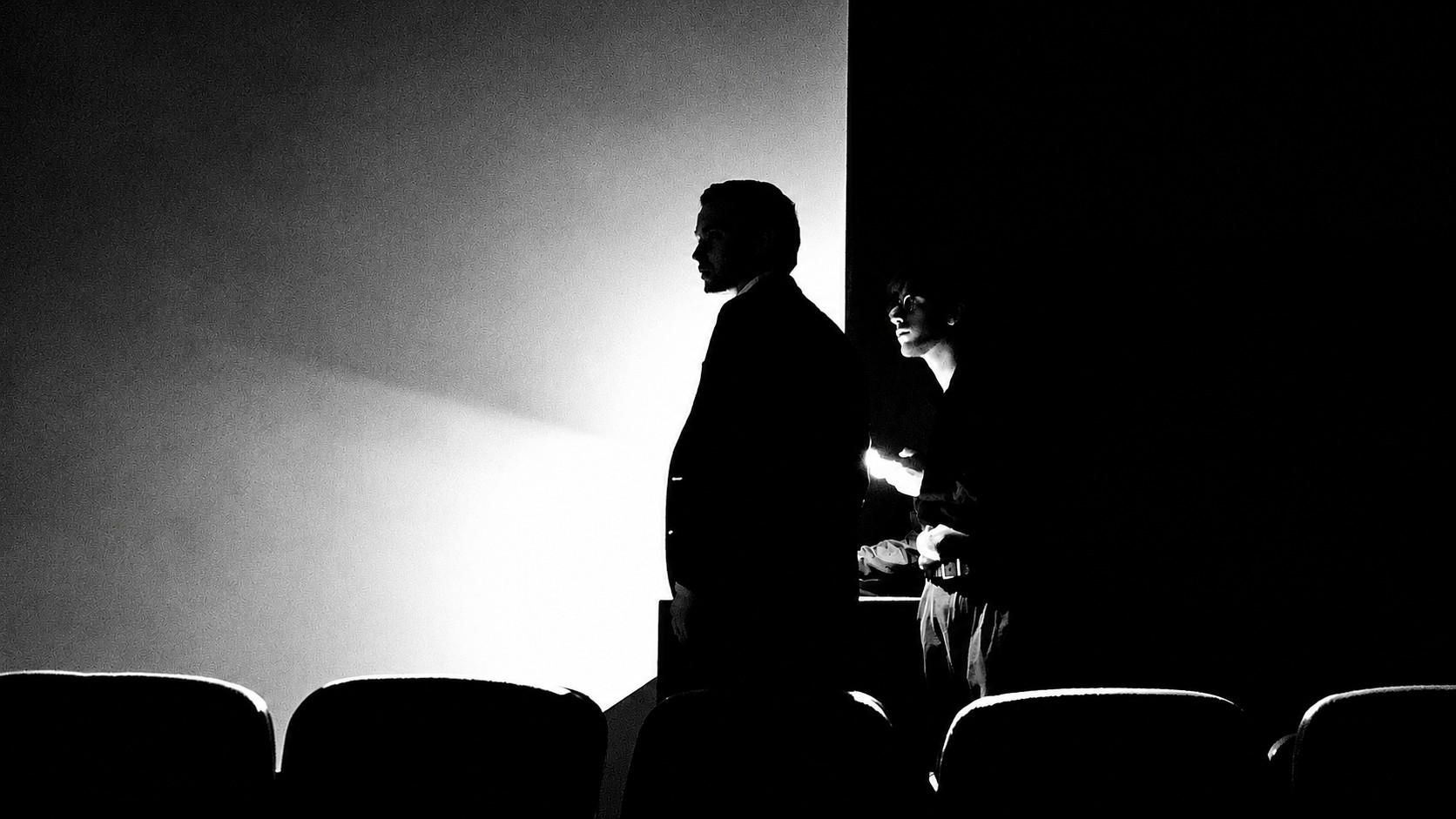Kai Helenius in a theater, silhouetted in profile against the projector light.